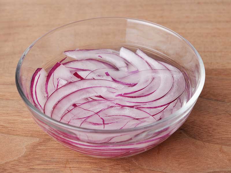 赤玉ねぎは薄切りにし、水にさらして水けを切ります。トマトは半月の薄切り（または薄い輪切り）にします。