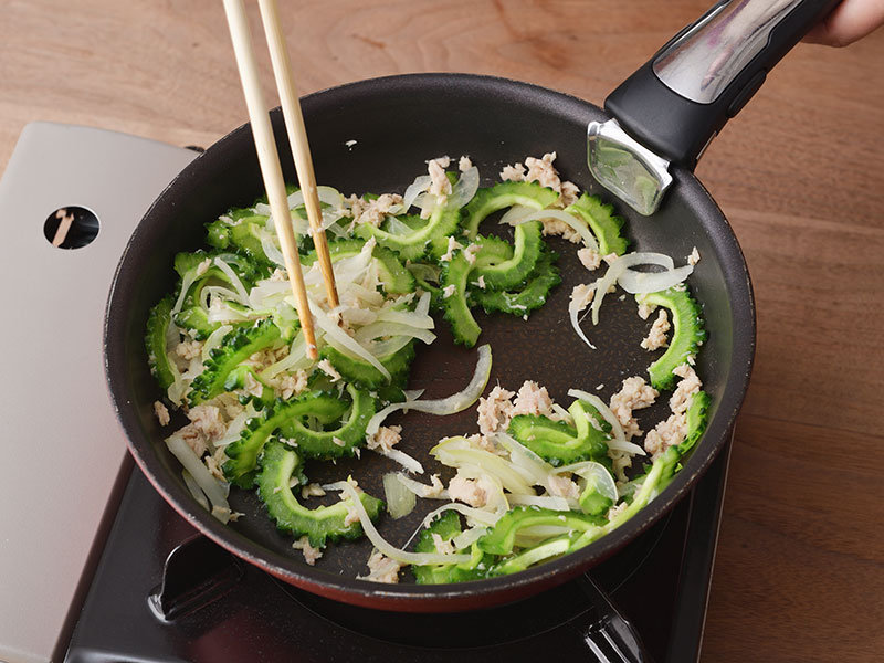 フッ素樹脂加工のフライパンを中火で熱し、玉ねぎとツナを炒めます。ゴーヤーを加えてさらに炒めます。