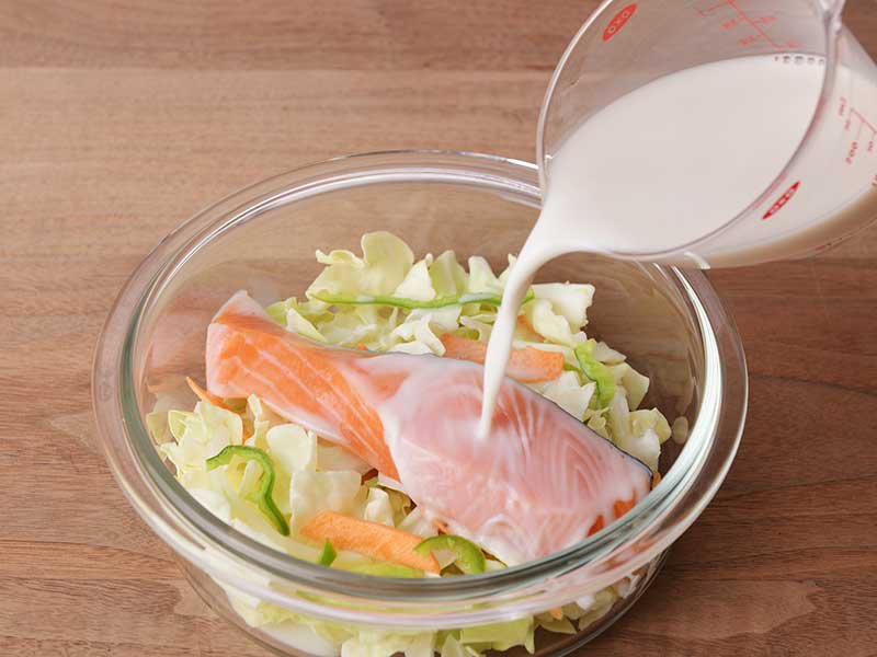 耐熱容器に野菜、鮭、調味料の順にのせ、アーモンドミルクをかけます。