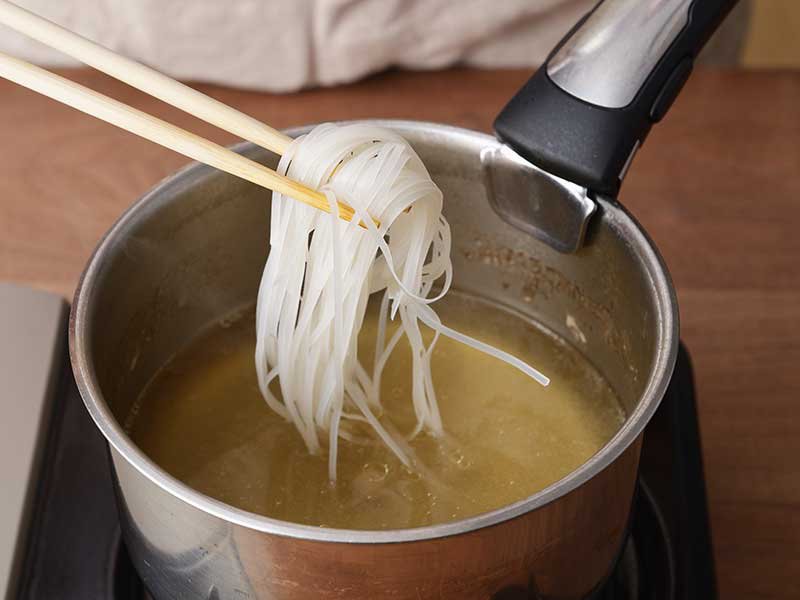 鶏肉を取り出し、ナムプラー、１の麺を加えて中火にし、ひと煮立ちさせます。